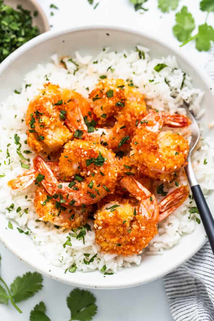 A bowl of rice with shrimp on top.