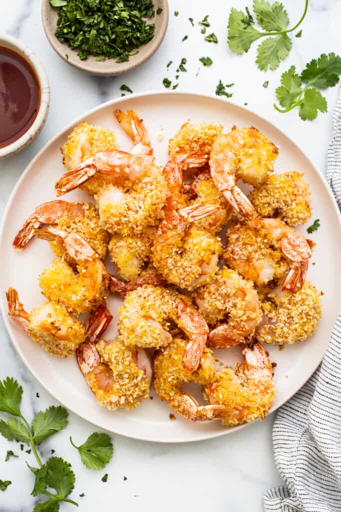 Fried shrimp on a plate with herbs and sauce.