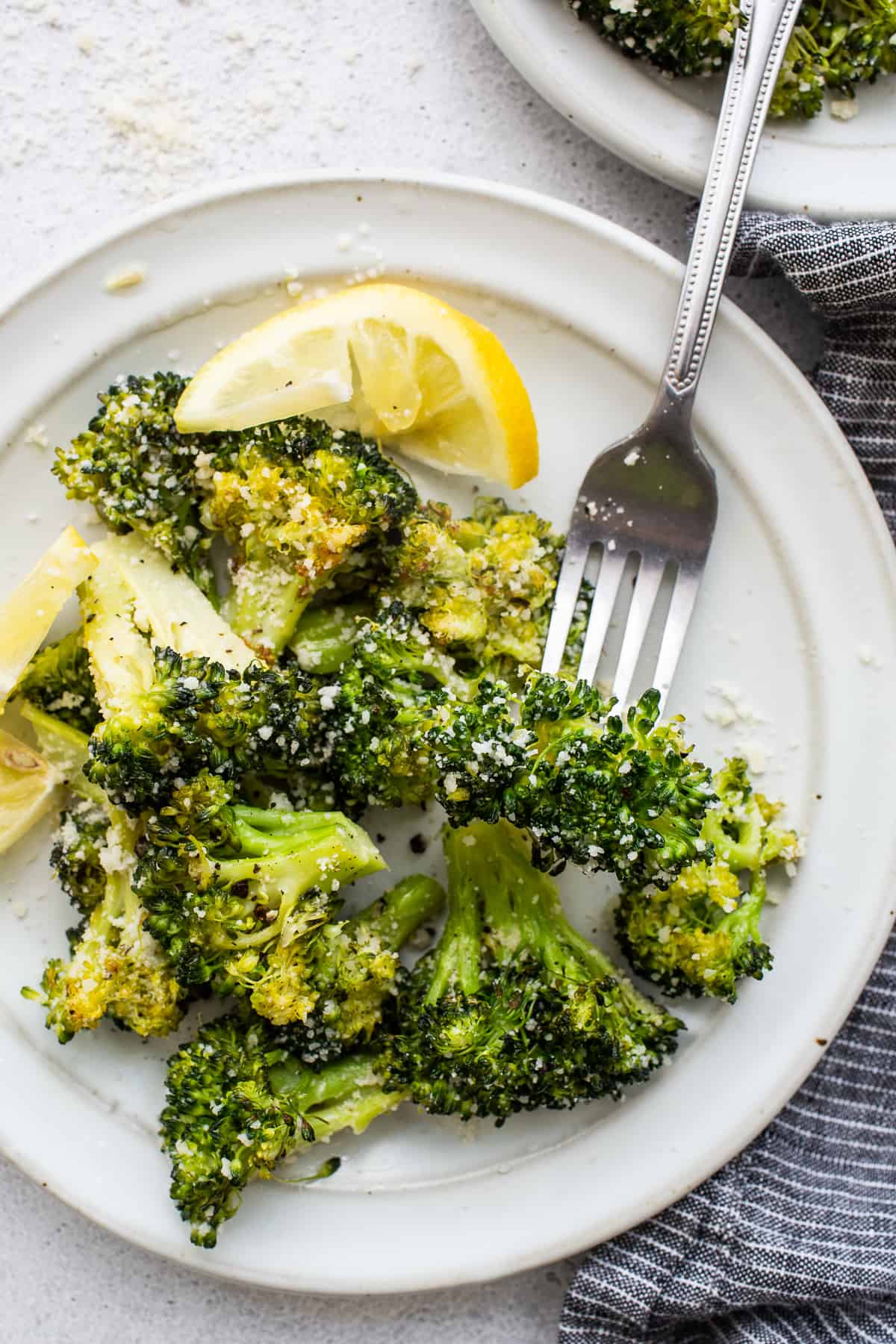 Roasted broccoli on a plate with a fork.