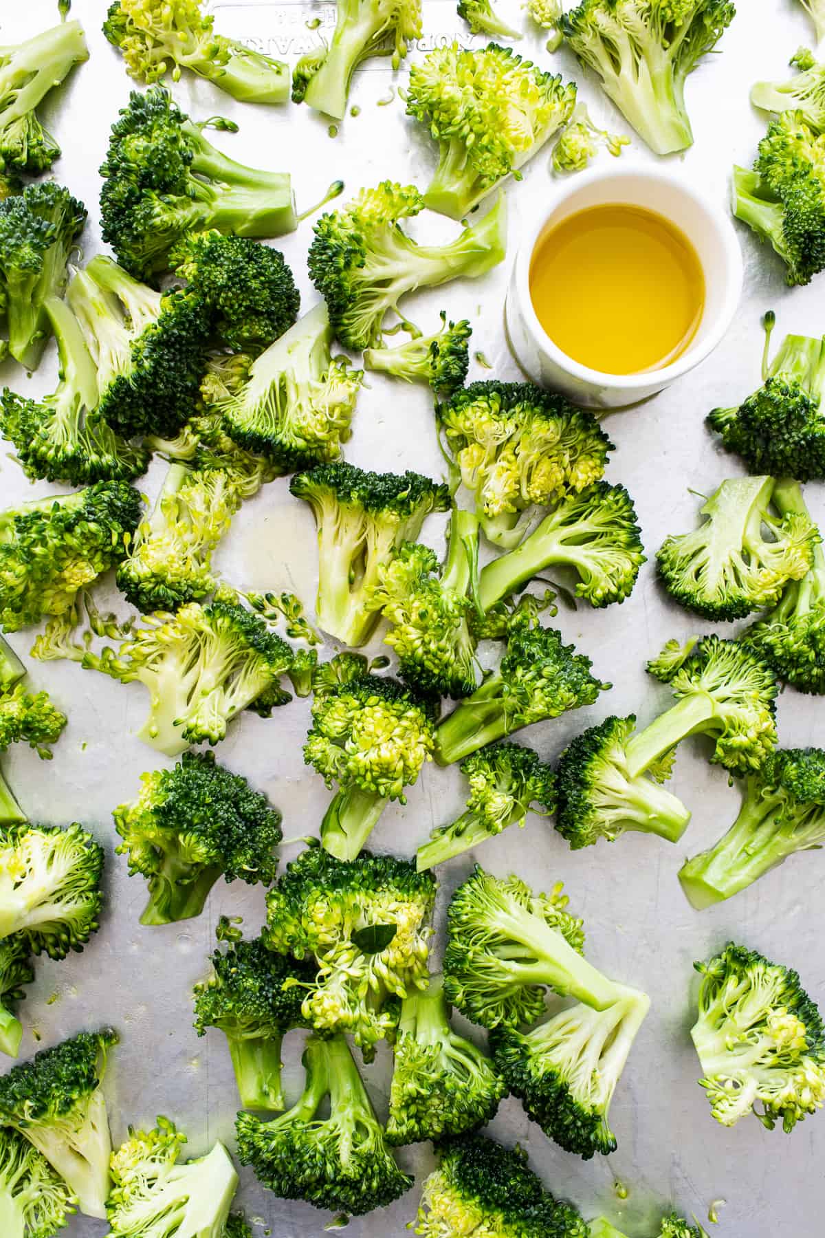 Broccoli florets and a bowl of olive oil.