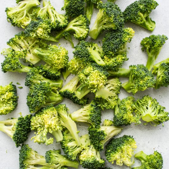 A pile of chopped broccoli on a white surface.
