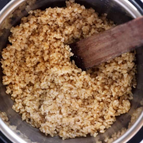 Brown rice in an instant pot with a wooden spoon.