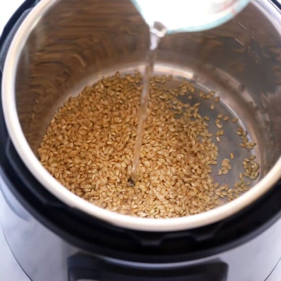 A liquid is being poured into a pot of grains.