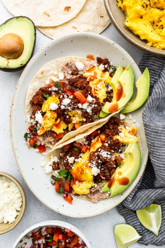 Breakfast tacos with eggs and avocado on a plate.