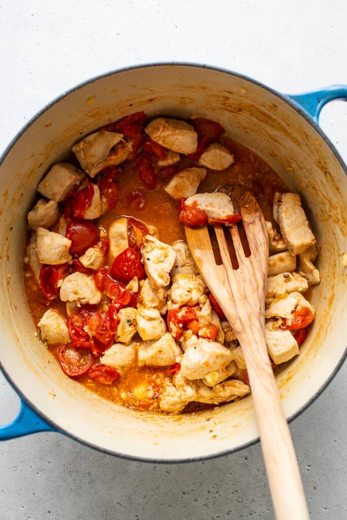 cooking chicken and tomatoes in large pot.