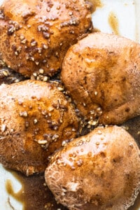 Chicken breasts in a baking dish with sauce and sesame seeds.