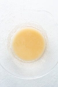 A glass bowl with a yellow liquid in it.