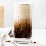 a tall glass of iced coffee on a table.