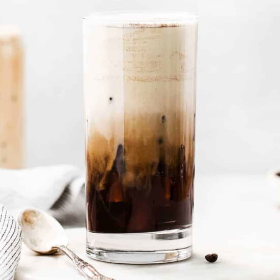 a tall glass of iced coffee on a table.
