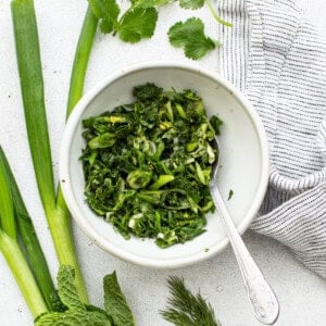 Fresh herbs in a bowl with a spoon.