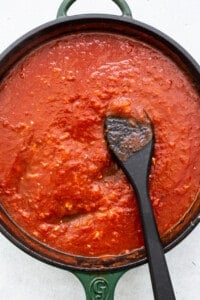 Tomato sauce in a pan with a spoon.