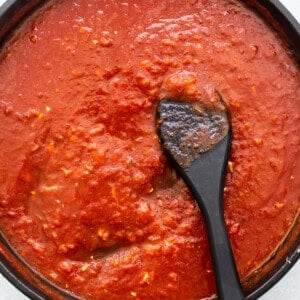 Tomato sauce in a pan with a spoon.