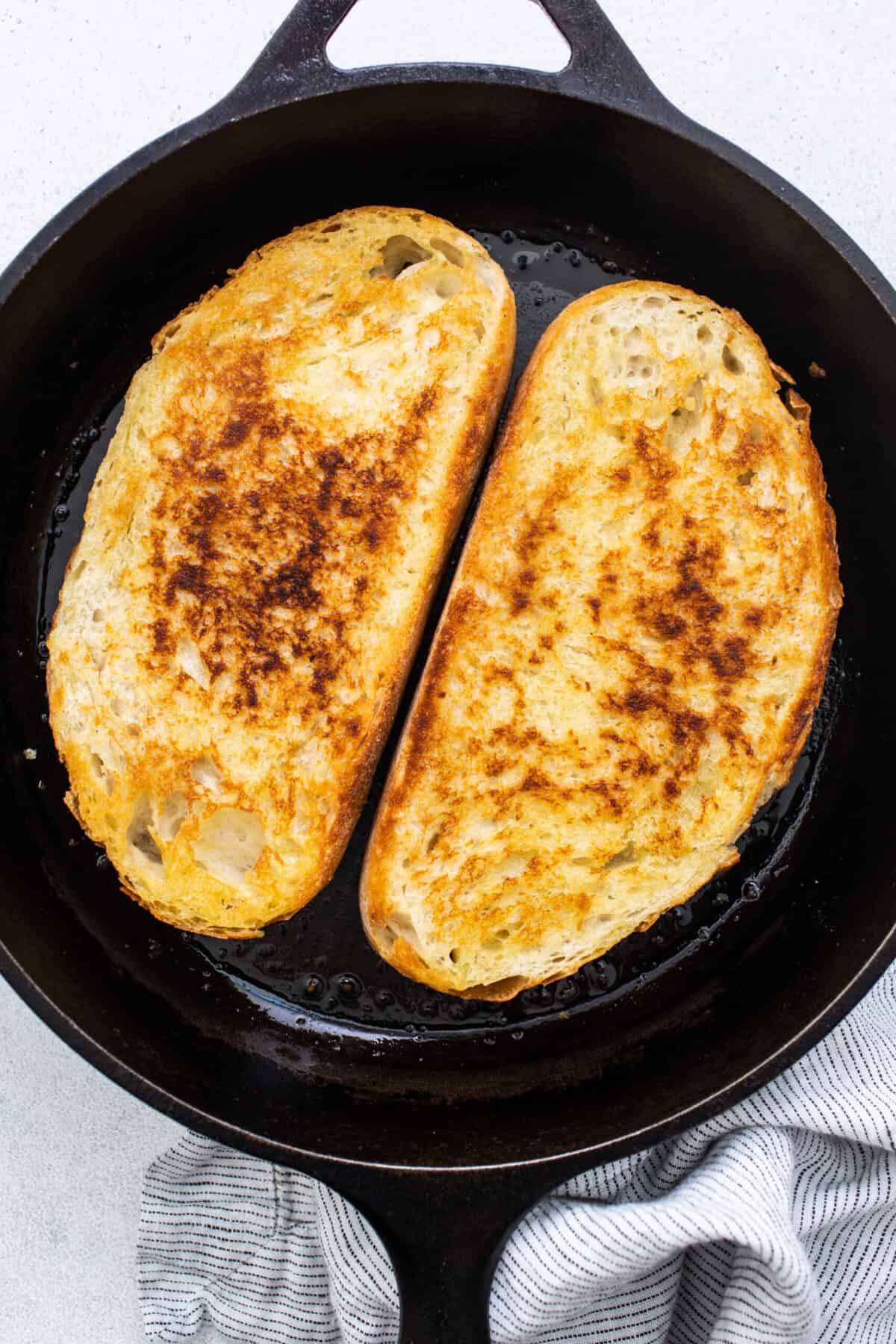 Two slices of french toast in a cast iron skillet.