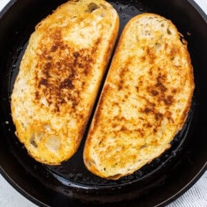 Two slices of french toast in a cast iron skillet.