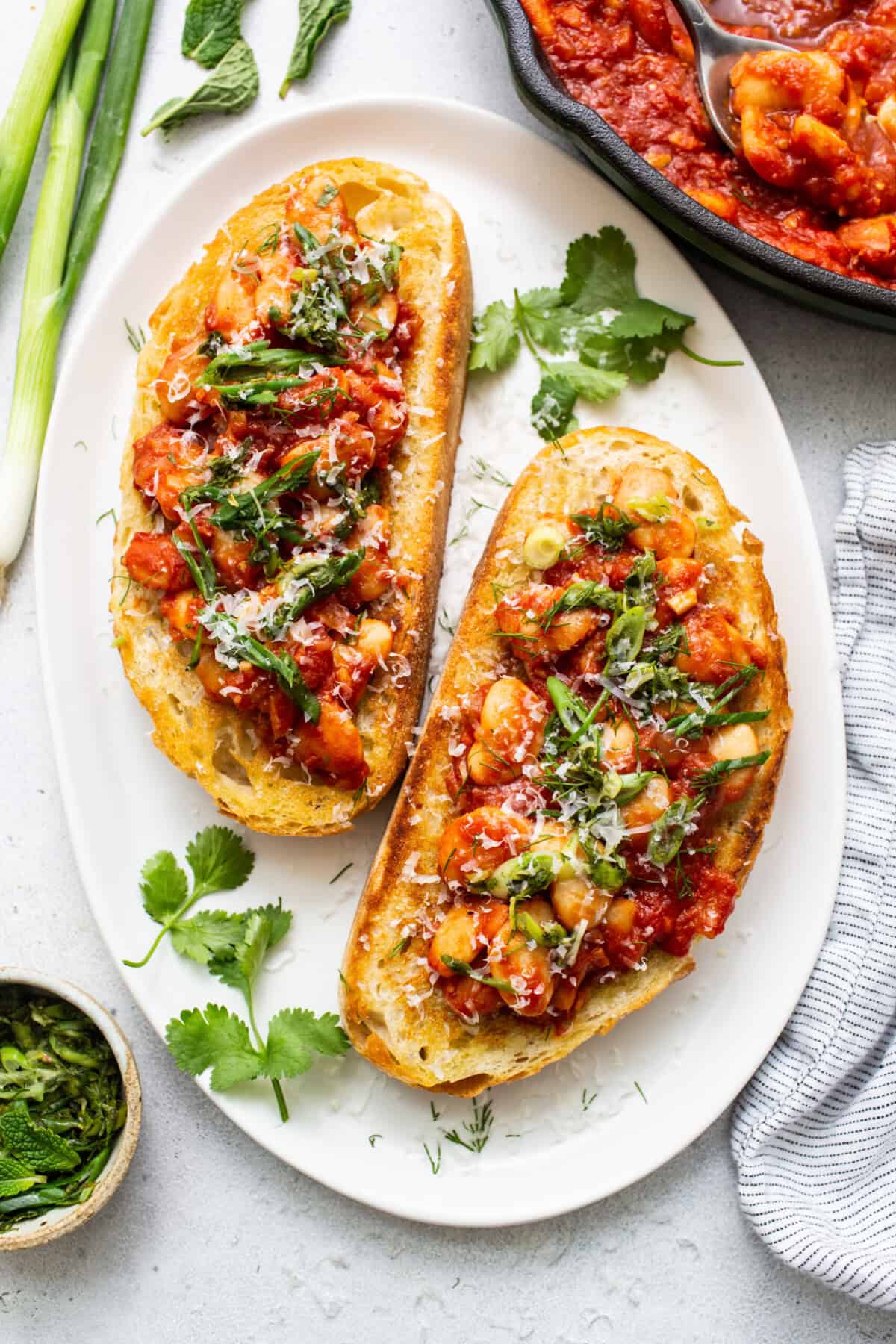 Two slices of bread with tomato sauce and herbs on a plate.