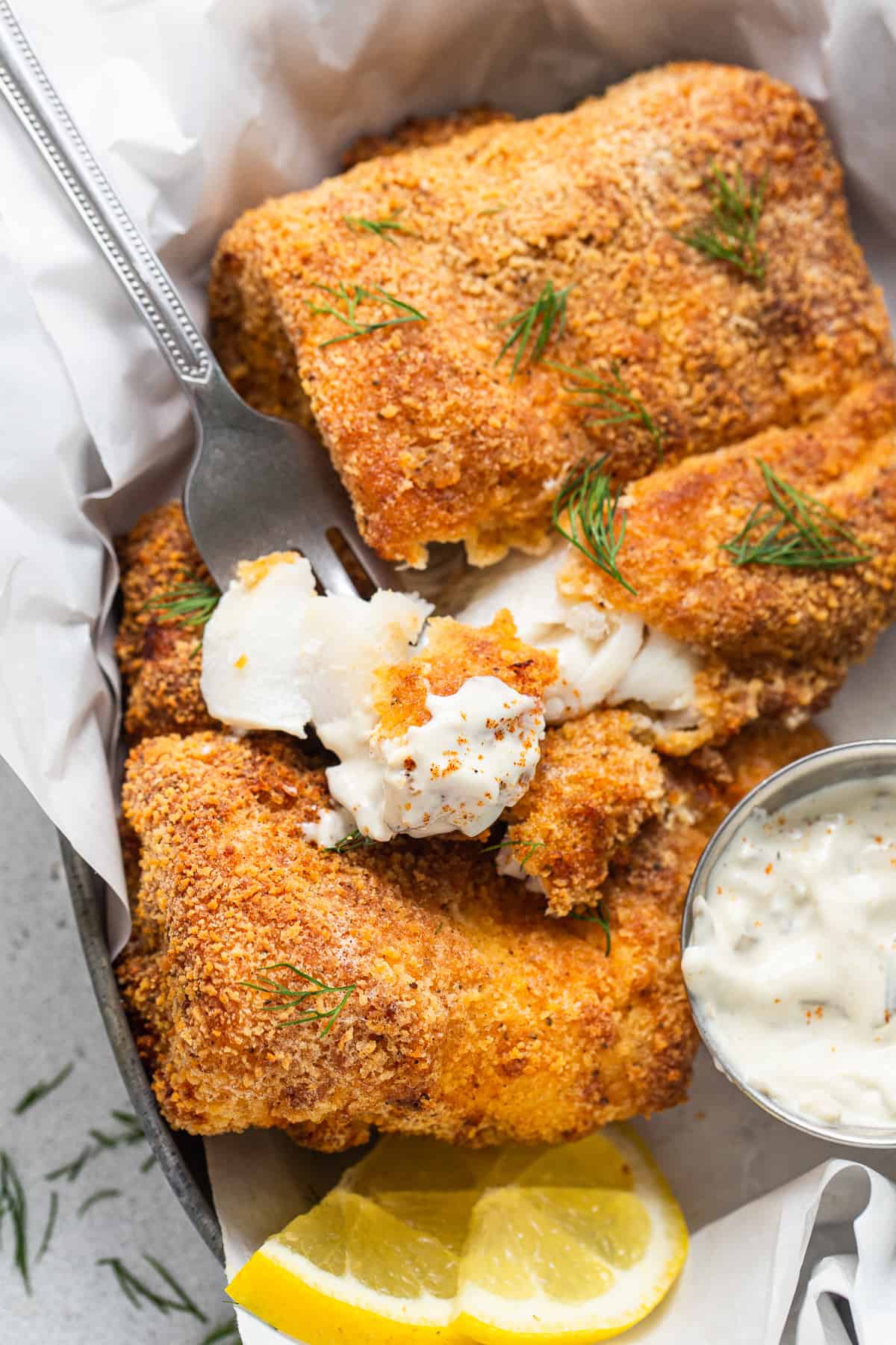 Crispy air fryer fish in a basket with tartar sauce.