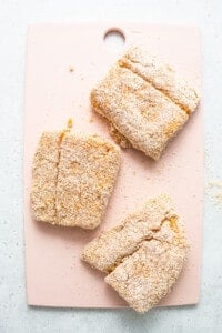 Three pieces of cookies on a pink cutting board.