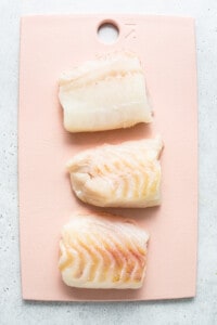 Raw cod on a cutting board.