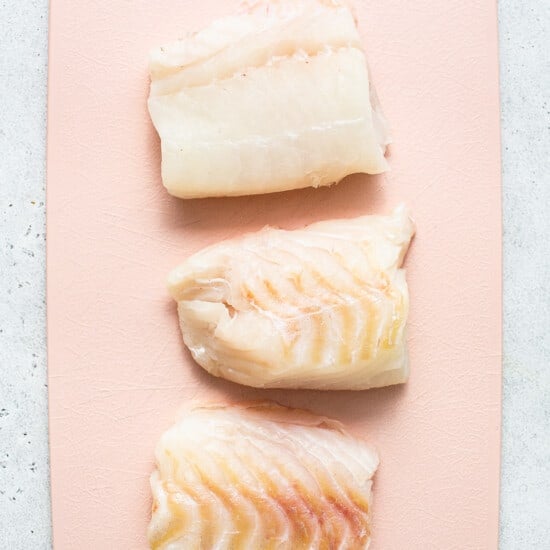 Raw cod on a cutting board.