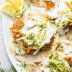 Fish tacos with slaw and lemon wedges.