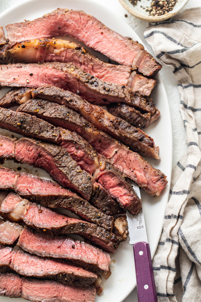 Bife fatiado da fritadeira em um prato com uma faca.