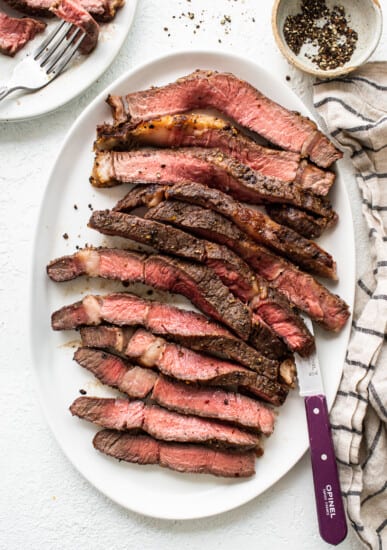 Sliced air fryer steak on a plate with a knife.