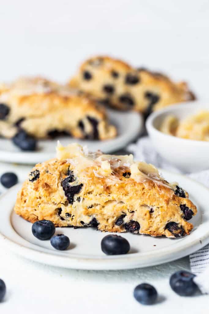blueberry scones on a plate with a bite taken out of one.