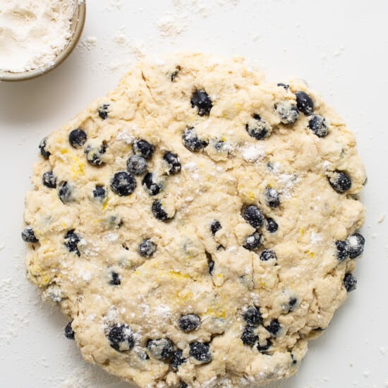 a cookie dough with blueberries and powdered sugar.