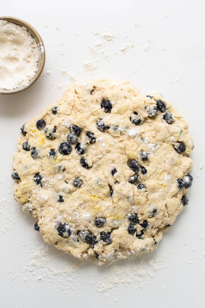 a cookie dough with blueberries and powdered sugar.