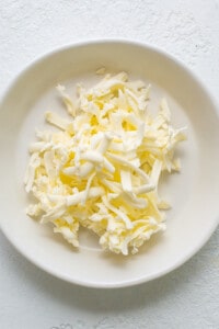a white plate topped with shredded cheese on top of a table.