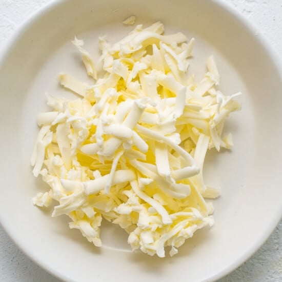 a white plate topped with shredded cheese on top of a table.
