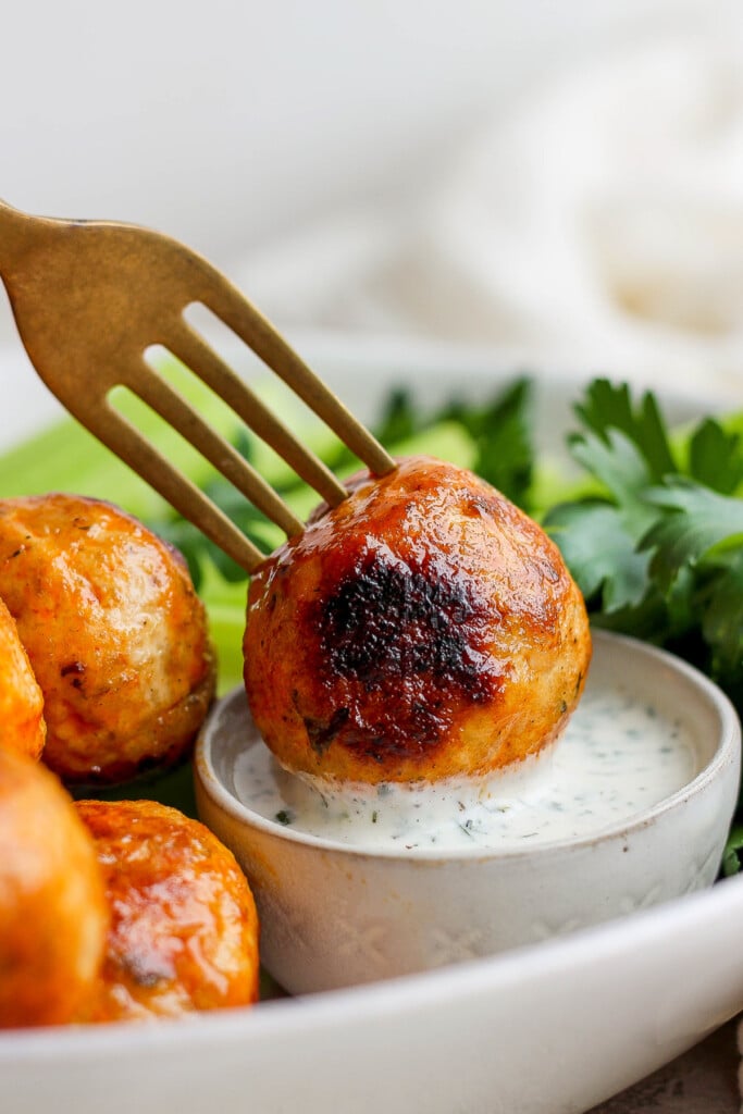 dipping meatball into dressing.