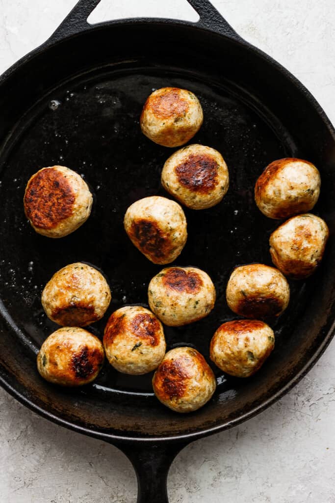 cooking meatballs in cast iron pan.