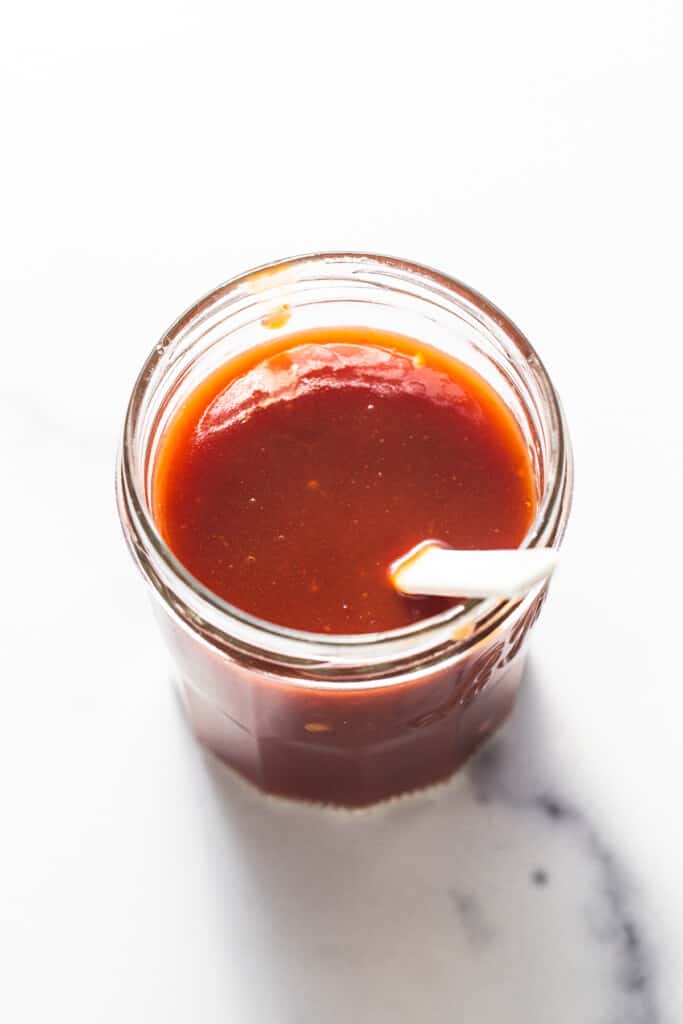 a jar of firecracker sauce with a spoon.