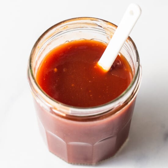 homemade firecracker sauce in a jar with a spoon.
