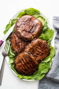 Grilled mushrooms on a plate with spinach and a fork.