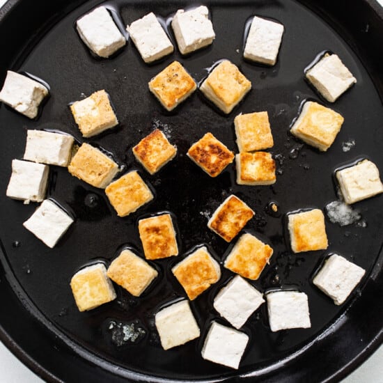 Tofu in a skillet on a white surface.