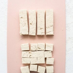 Tofu cubes on a pink cutting board.