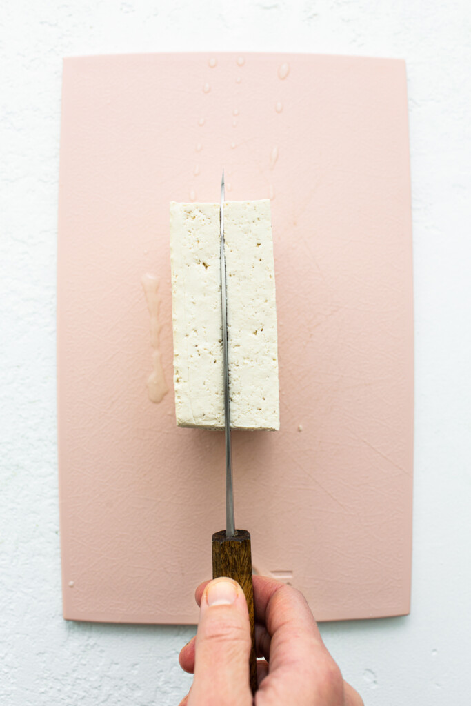 Cutting tofu on cutting board.