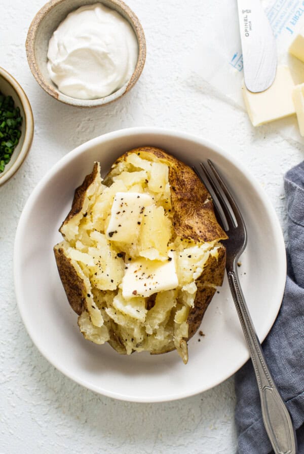 baked potato with butter in bowl.