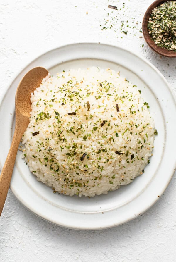 White rice on a white plate with a wooden spoon.