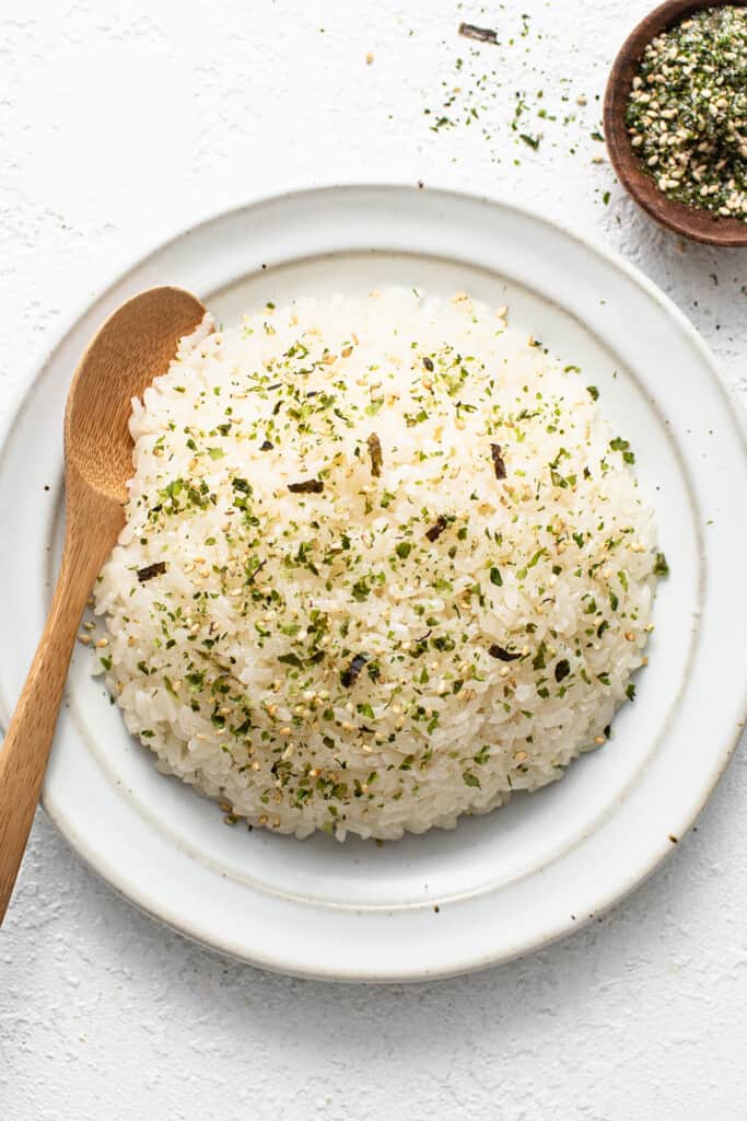 White rice on a white plate with a wooden s،.