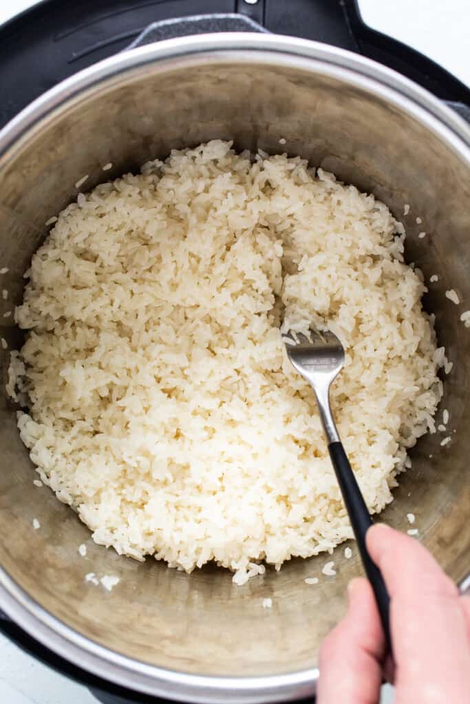 A person pouring rice into an instant ،.