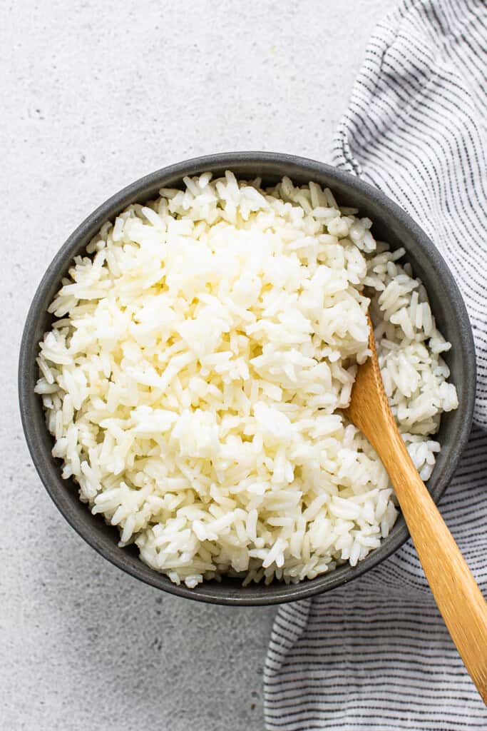 White rice in a bowl with a wooden s،.