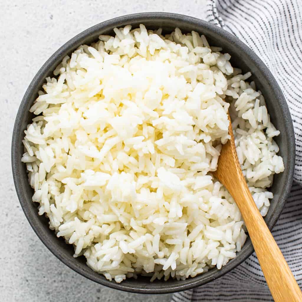 White rice in a bowl with a wooden spoon.