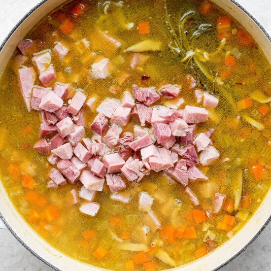 A pot of soup with ham and carrots.
