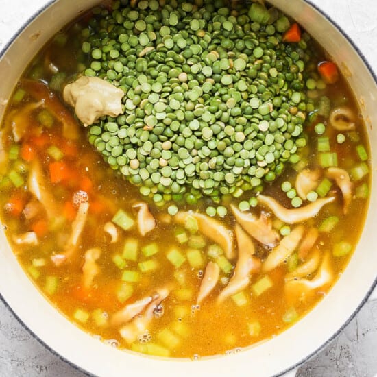 A pot of soup with peas and mushrooms.