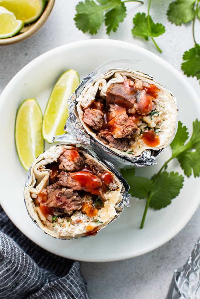 Steak burrito on a plate wrapped in foil.