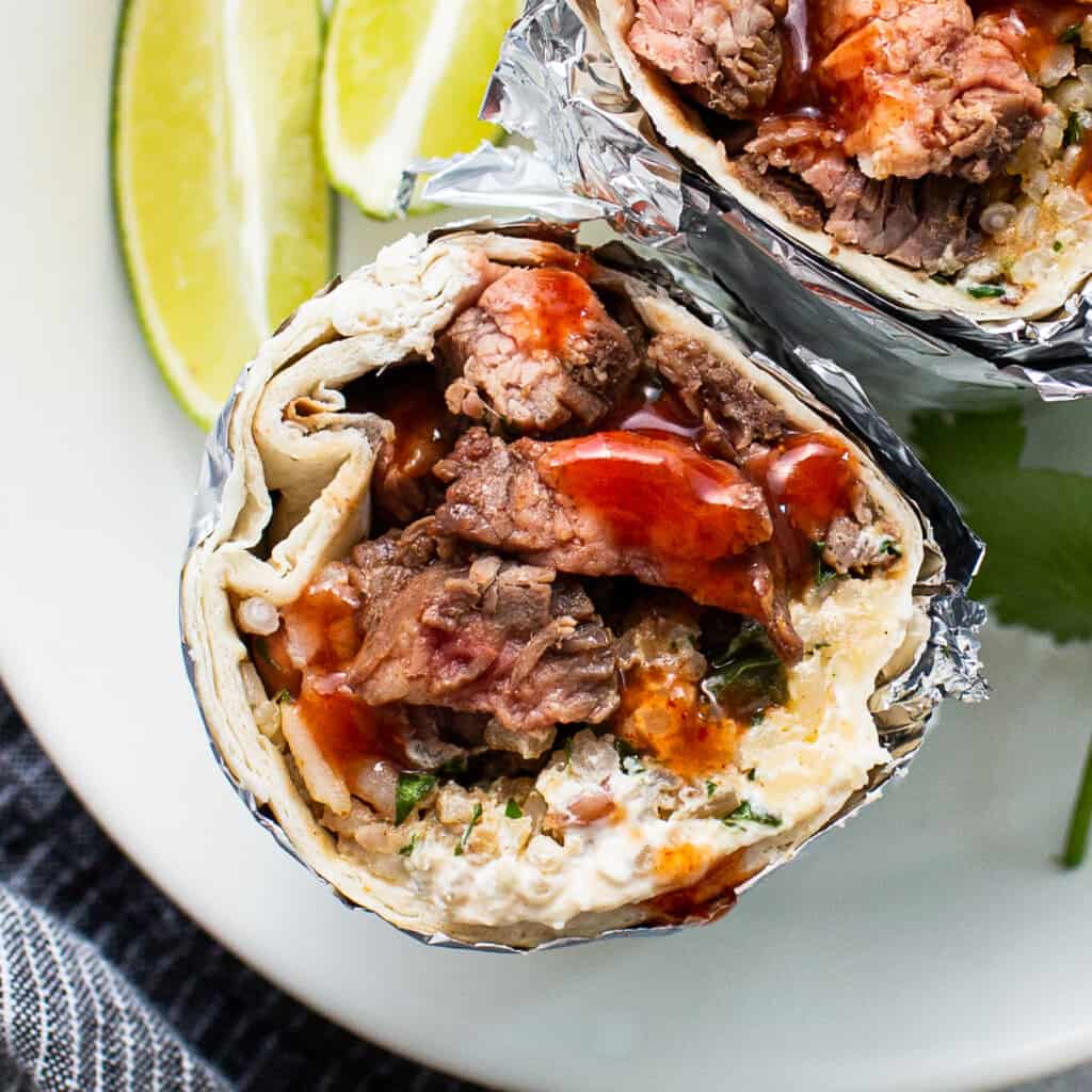 Steak burrito connected  a plate.