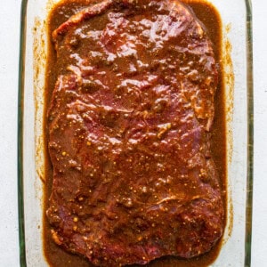 A glass baking dish with meat in a sauce.